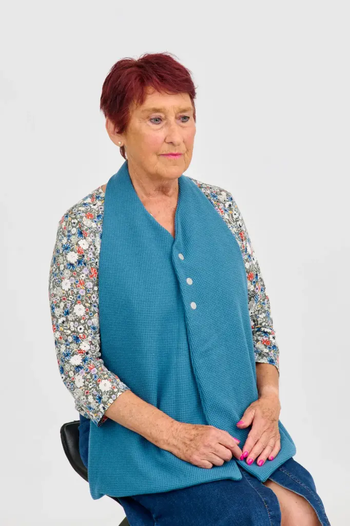 Scarf-shaped bib with impermeable interlayer and snap fastener closure at the front